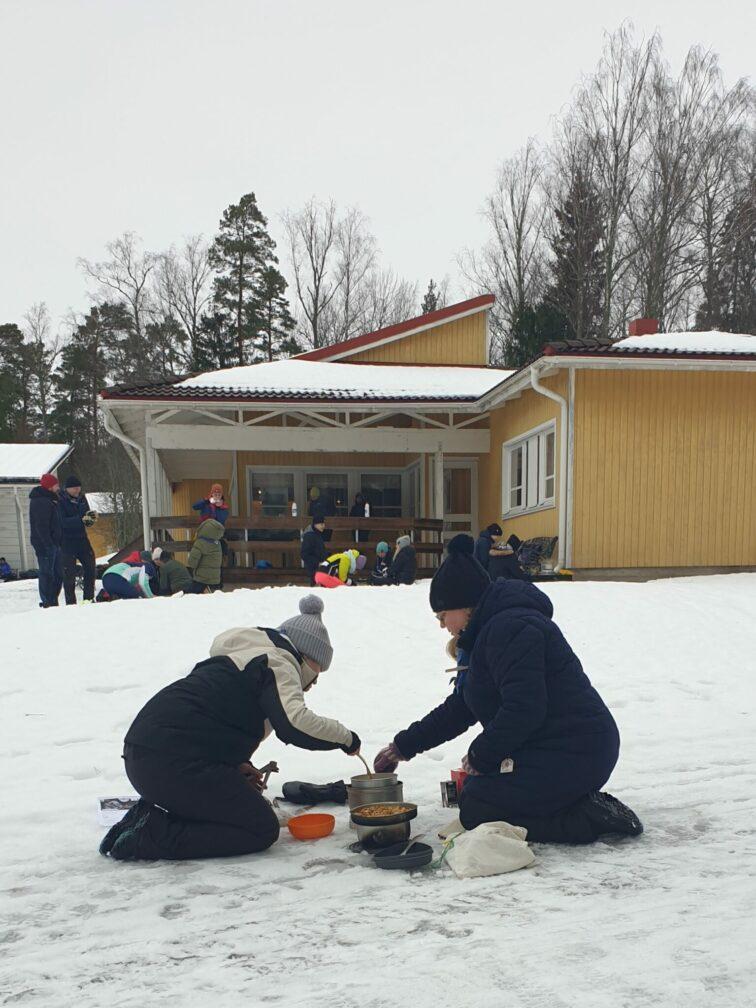 Partiolaisia kokkaamassa ulkona talvella.